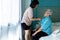 Asian female caregiver taking care of helping elderly patient get dressed,wearing clothes,button up on the shirt for happy senior