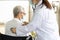 Asian Female doctor listening to sounds from the heart and lungs of senior woman at the back of the body with a stethoscope,health