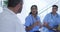 Asian female doctor sitting and discussing with diverse male colleagues at hospital staff meeting