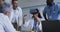 Asian female doctor at table using vr headset with a diverse group of colleagues gathered around her