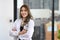 Asian female doctor in white uniform standing in medical office and smiling at camera.