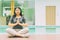 Asian female doing yoga sitting in a lotus hand posture at home outdoors