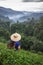 Asian female farmer in ribal costume on highland tea plantation with morning mist in Northern Thailand