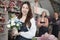 Asian female florist worker stands in front of a team in colorful flower shop.