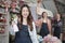 Asian female florist worker stands in front of a team in colorful flower shop.