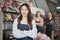 Asian female florist worker stands in front of a team in colorful flower shop.