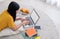 Asian female freelancer working on laptop computer at home.woman lying down on carpet at brick wall.working online lifestyle.mock