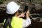 Asian female geologist researcher is analyzing rocks with a smartphone in a natural park. Exploration Geologist in the Field.