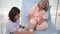 Asian female nurse bandaging foot of elderly woman patient