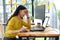 Asian female programmer wears a yellow shirt, looks at the laptop screen and shows a serious pose