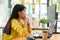 Asian female programmer for yellow shirt sitting with a hand on her chin,She stared at the computer screen and pondered