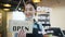 Asian female restaurant owner flip the shop`s sign placard from Closed to Open and smile, slow motion
