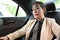 Asian female senior executive manager sits on the backseat on her private luxury car