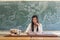 Asian female teacher sitting in a classroom marking homework of the students