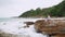 Asian female traveler on rock cliff by the sea looking at the view in front. woman taking fresh air near the sea after success lit