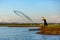 Asian Fisherman throwing a net for catching freshwater fish in the early morning