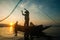 Asian fisherman on wooden boat casting a net for catching freshwater fish