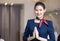 Asian flight attendant posing with smile at middle of the aisle inside aircraft passenger seat on the background