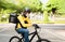 Asian food delivery rider man wear face mask and helmet ride cycling with backpack using mobile phone and food delivery of order