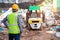 Asian foreman stand and watch the workers at recycle waste factory with a forklift on the background