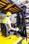 Asian fork lift truck driver lifting pallet in storage