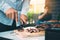 Asian friends are using a knife and a fork to cut the grilled meat on the chopping board to bring food together with friends