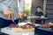 Asian friends are using a knife and a fork to cut the grilled meat on the chopping board to bring food together with friends