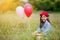 Asian girl with balloons plays in a field