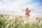 An Asian girl on a beautiful spring meadow at sunset. She wears a pink dress and wide-brimmed hat.