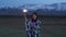 An Asian girl dressed in a blanket holds a sparkler in her hands. Sunset, snowy mountains in the background