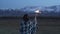 An Asian girl dressed in a blanket holds a sparkler in her hands. Sunset, snowy mountains in the background