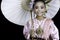 An Asian girl dressed in traditional costumes and holding a paper umbrella, a famous handicraft in northern Thailand