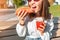 Asian girl eating taco outside and drinking beverage. Mexican fastfood cuisine. Tasty and spicy snack in park
