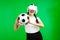 Asian girl football fan in vr headset holding a soccer ball isolated green wall background, football sport and Metaverse