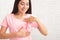 Asian Girl Framing Cancer Ribbon Symbol On T-Shirt Posing Indoors