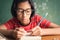 Asian girl with glasses is taking notes in her class notebook, Educational concept