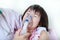 Asian girl having respiratory illness helped by health professional with inhaler.