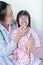 Asian girl having respiratory illness helped by health professional with inhaler.