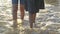 Asian girl with her sister walking hand in hand along together leisurely on the beach with waves washed up on the coast.