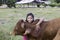 An Asian girl lovingly hugs her cow in a ranch.