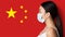 Asian girl in medical mask looking at China country flag