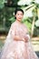 Asian girl in an old rose pink color knee length fluffy dress with high heel slingback shoes and ceremonial thread on her wrist.