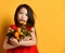 Asian girl in red blouse. Looking surprised, holding an armful of tangerines and oranges, posing on orange background. Close up
