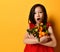 Asian girl in red blouse. Looking surprised, holding an armful of tangerines and oranges, posing on orange background. Close up