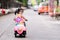 Asian girl ride pink electric motorbike playing in the evening. Back of the child is cute. Children turned to look at the camera.