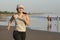 Asian girl running on the beach - young attractive and happy Korean woman doing jogging workout at beautiful beach enjoying