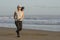 Asian girl running on the beach - young attractive and happy Korean woman doing jogging workout at beautiful beach enjoying