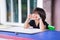 Asian girl sits with her arms on her chin while waiting to study art. Child is sitting blankly. Kid gets bored while waiting.