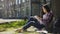 Asian girl sitting under tree, making sketch of surroundings in notebook, artist