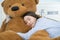 Asian girl sleeping on the bed with a big brown teddy bear.